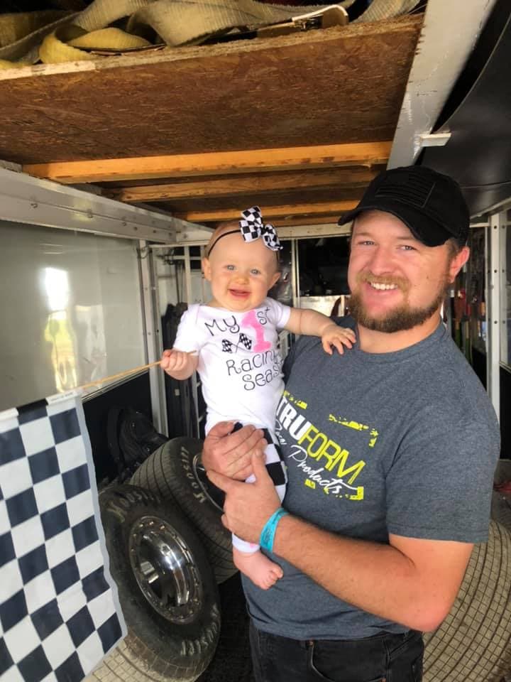 Ryan with baby Kinsley in the hauler wearing a 'My 1st Racing Season' onesie